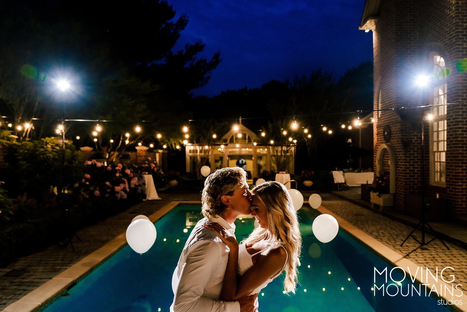 Bride and Groom kiss in front of a pool at night